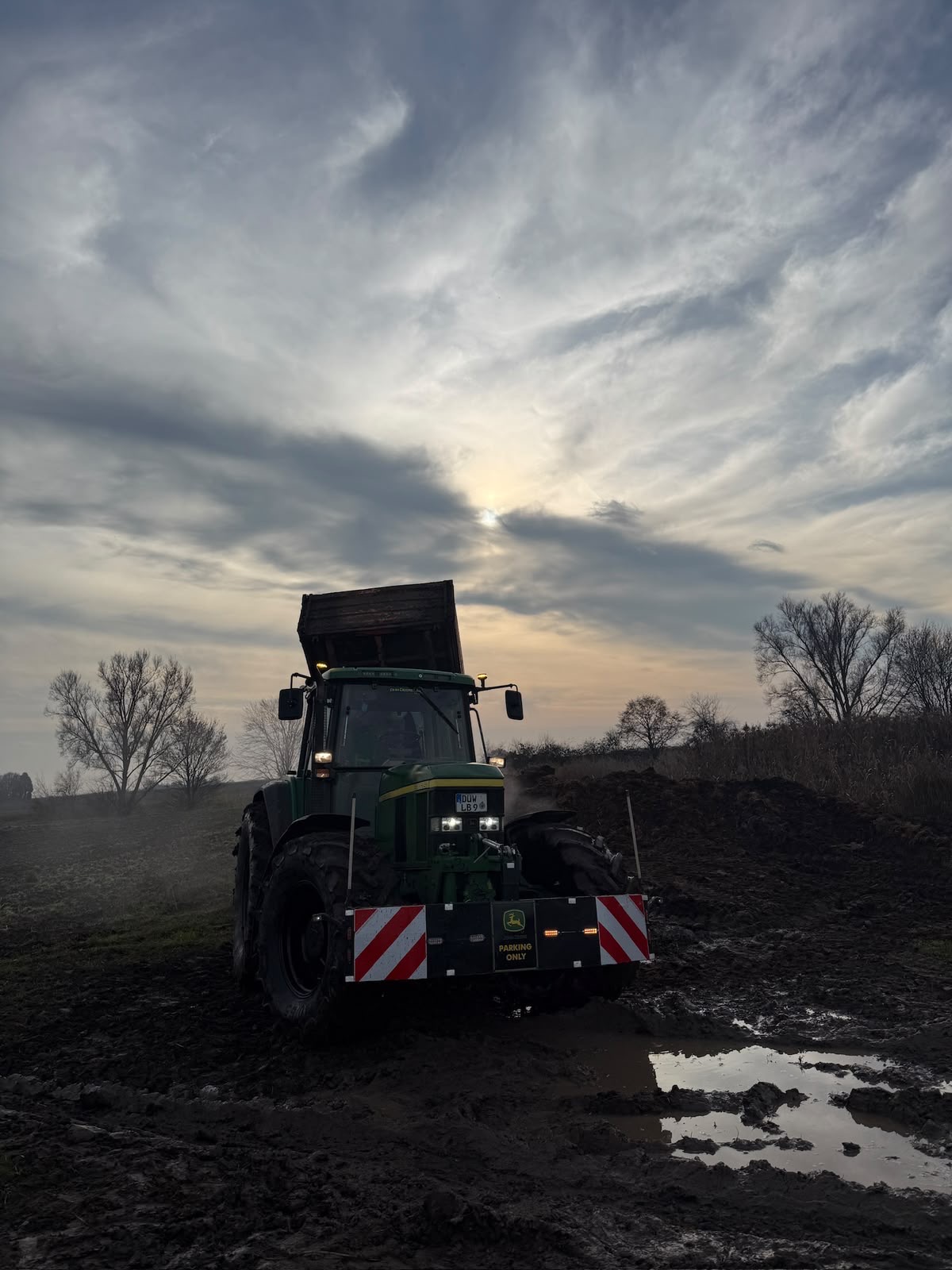 Traktor im Feld bei Sonnenuntergang